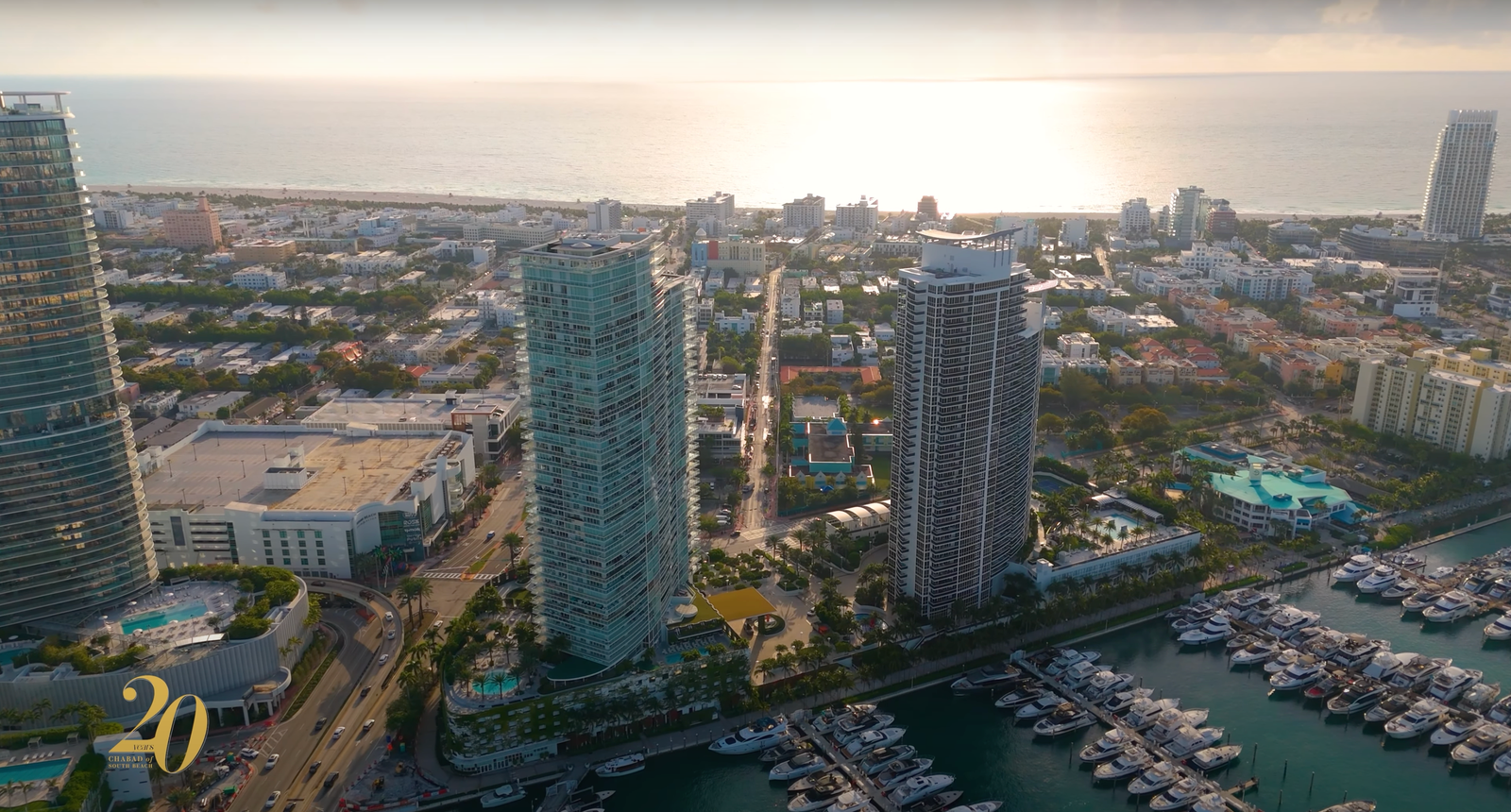 Aerial view of coastal high-rise towers, a marina full of boats and ocean at sunset